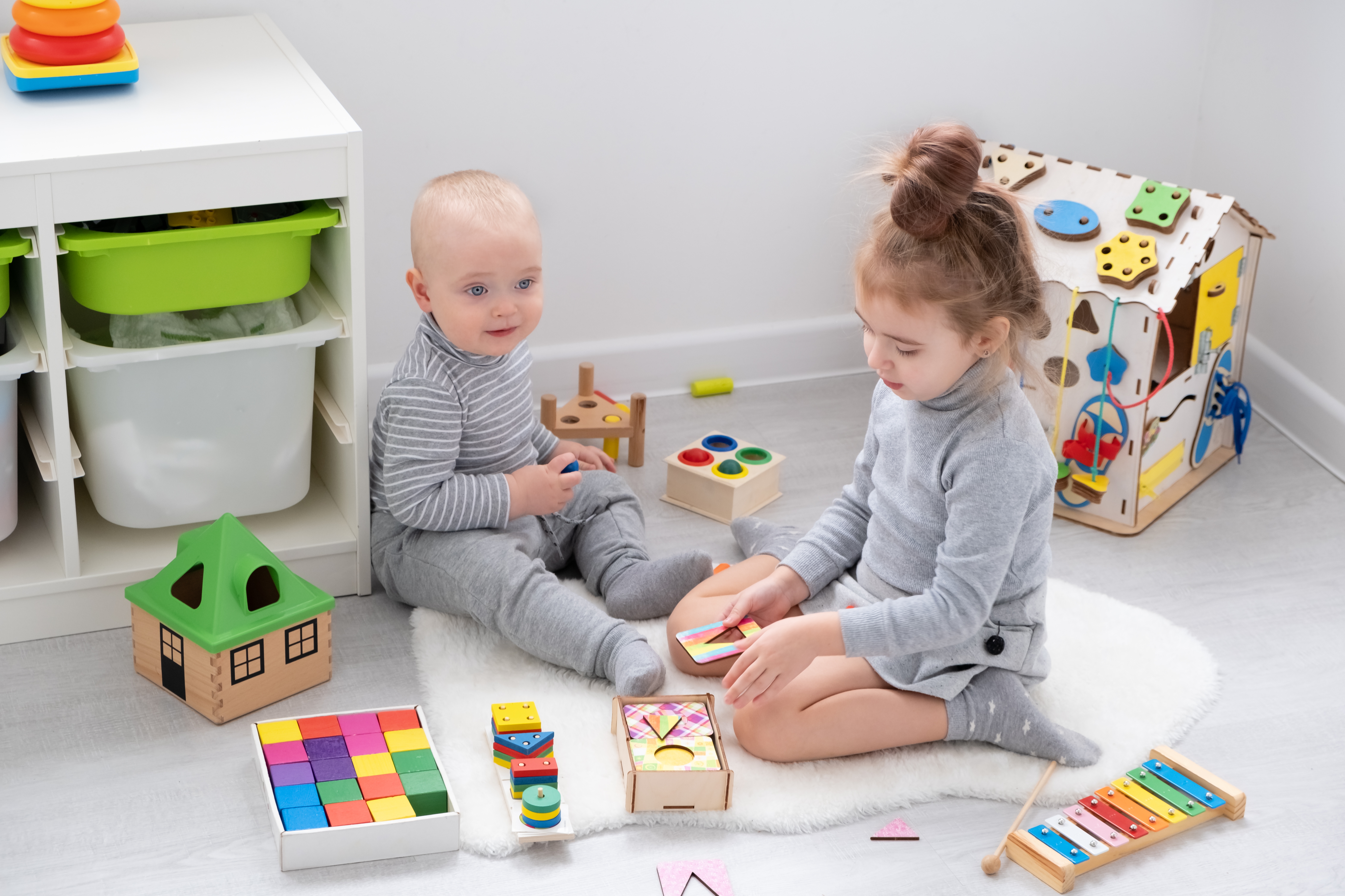 Jeune enfant jouant avec sa grande sœur avec des jouets en bois 